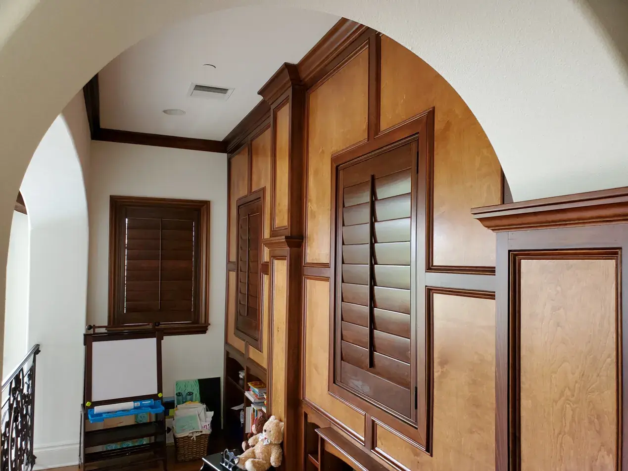Stained wood shutters in office with custom millwork