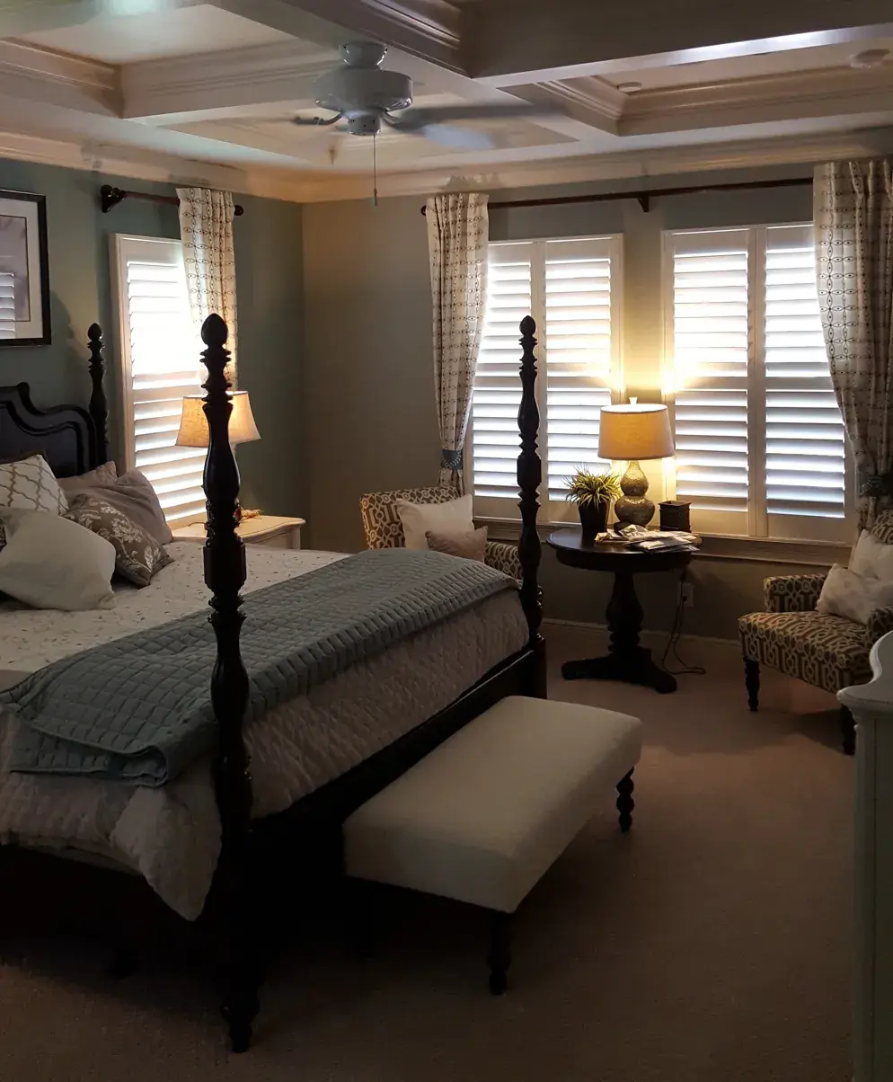 Plantation shutters in master bedroom with 4-poster bed and coffered ceiling