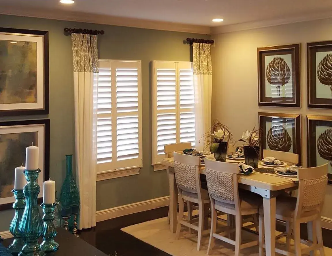 Plantation shutters with drapes in dining room