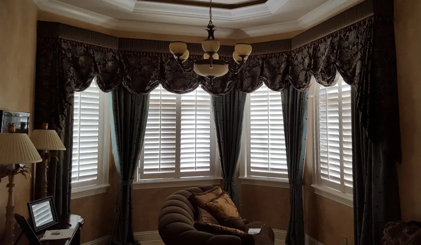 Curved bay window shutters with drapes in living room