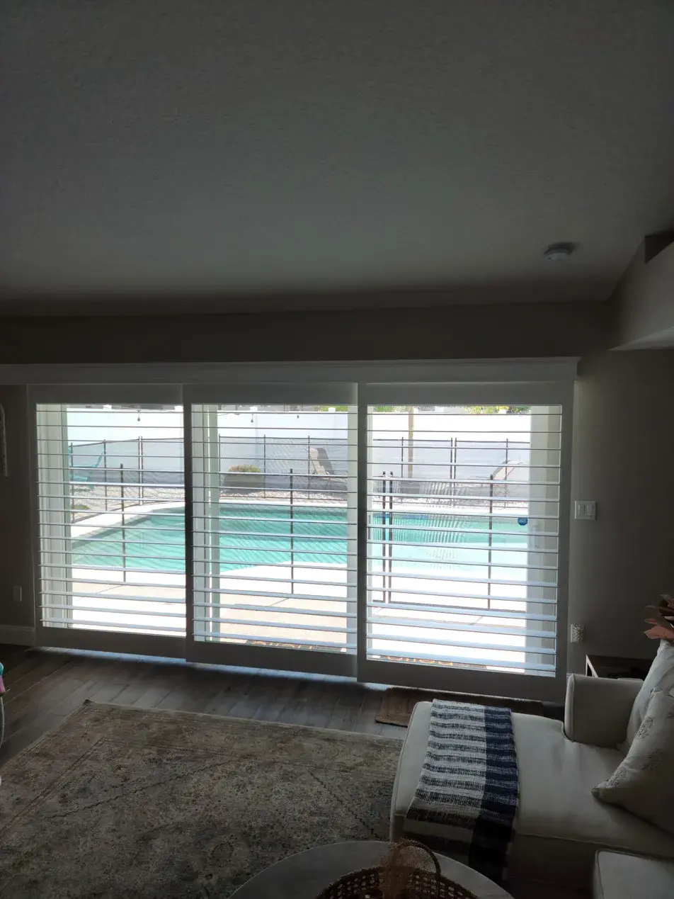 Bypass sliding shutters in living room with pool view